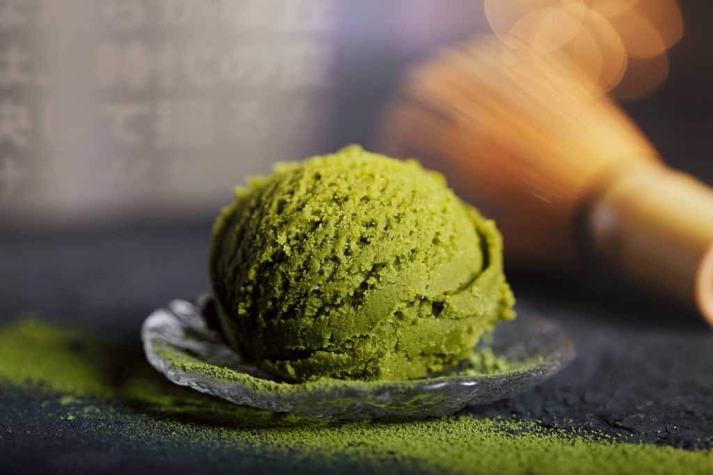Bola de sorvete verde servida em recipiente de vidro sobre superfície escura