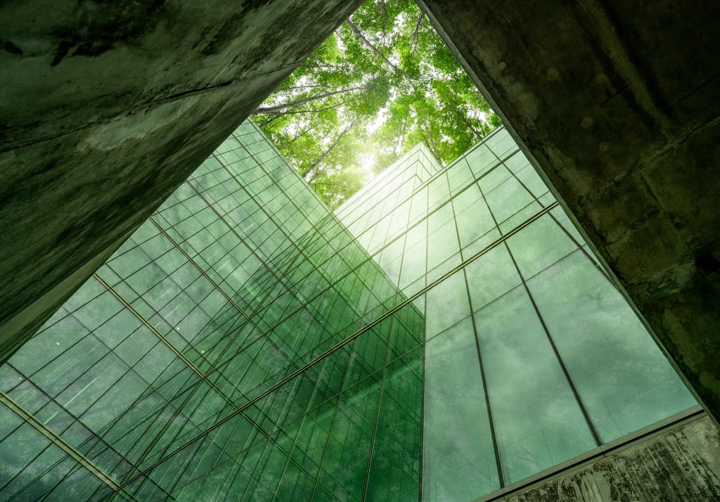 Edifício envidraçado com reflexos de árvores e abertura superior para a luz natural