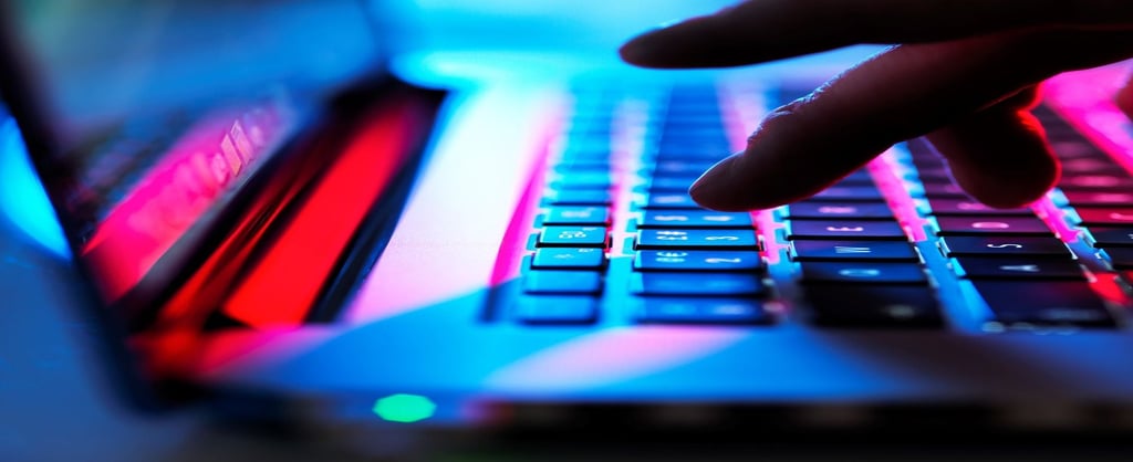 Mão digitando em teclado de notebook iluminado com luzes neon