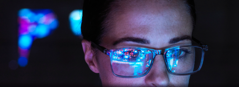 Rosto de profissional com óculos refletindo dados e interfaces digitais