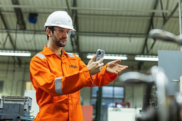 Profissional da LRQA realizando inspeção digital em instalação industrial com uso de smartphone
