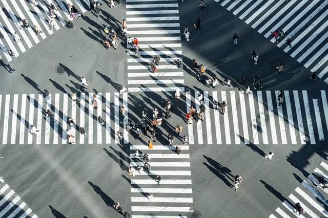Vista aérea de pedestres atravessando uma faixa em grande cruzamento urbano