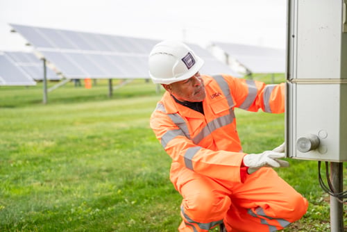 Especialista de LRQA inspeccionando equipos en una instalación con paneles solares, representando el enfoque sostenible y el compromiso con operaciones más responsables.
